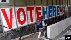 FILE - A voter passes a large sign before voting in Minneapolis.