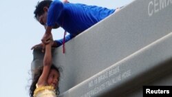 Un hombre ayuda a una niña a subirse a un vagón mientras se unen a otros migrantes centroamericanos (no fotografiados) en el tren de carga conocido como "La Bestia" durante su viaje hacia Estados Unidos, en Ixtepec, México.