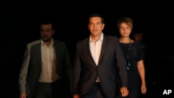 ນາຍົກລັດຖະມົນຕີ ກຣິສ ທ່ານ Alexis Tsipras (ກາງ) ກຳລັງຢ່າງອອກມາຈາກ ທຳນຽບປະທານາມິບໍດີ ຫລັງຈາກ ພົບປະກັບ ປະທານາທິບໍດີ ກຣິສ ທ່ານ Prokopis Pavlopoulos.