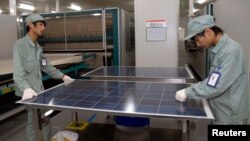 FILE - Employees work on a solar panel production line at Suntech Power Holdings headquarters in Wuxi, Jiangsu. 