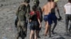 FILE - A female migrant is led by a Spanish female soldier as she is deported to Morocco after she crossed the border swimming from Morocco to Spain, at El Tarajal beach, in Ceuta, Spain, May 19, 2021. 