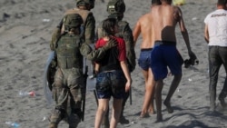 FILE -Seorang migran perempuan dikawal seorang tentara perempuan Spanyol saat dideportasi ke Maroko setelah dia melintasi perbatasan dengan berenang dari Maroko ke Spanyol, di pantai El Tarajal, di Ceuta, Spanyol, 19 Mei 2021.