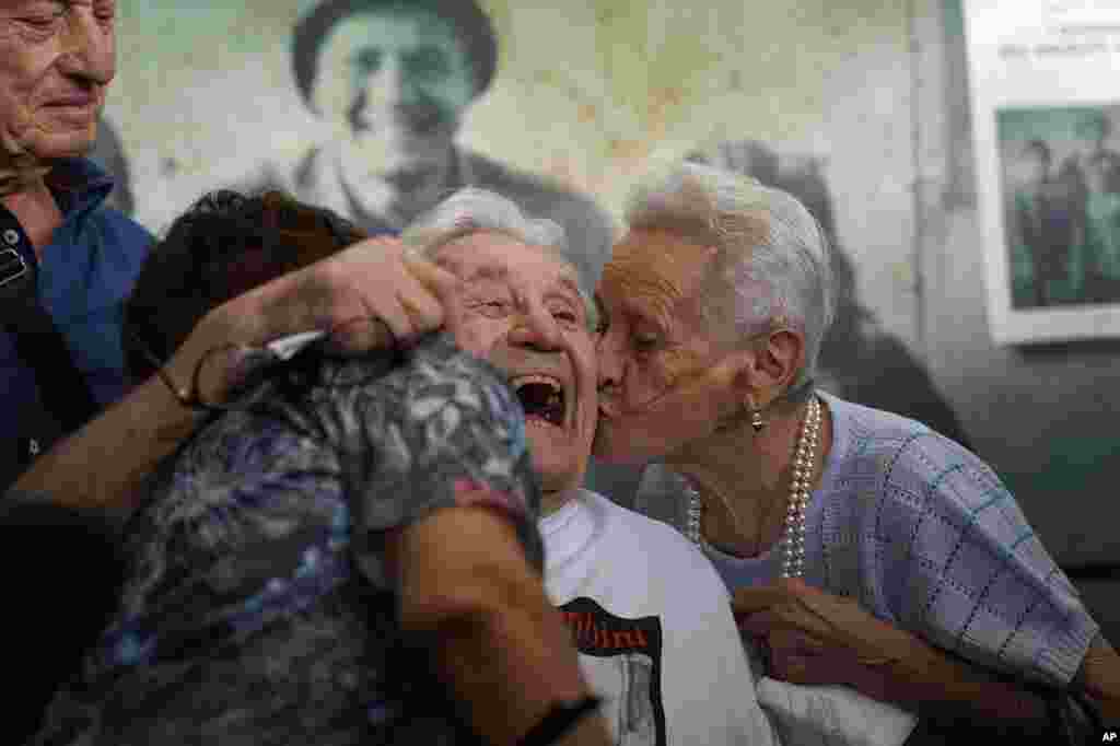 Martin Adler, center, a 97-year-old retired American soldier, receives a kiss by Mafalda, right, and Giuliana Naldi &mdash; siblings he saved during World War II &mdash; at Bologna&#39;s airport, Italy.