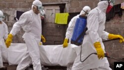 Trabajadores de la salud cargan el cuerpo de una mujer que se sospecha murió de ébola en Monrovia, la capital de Liberia.