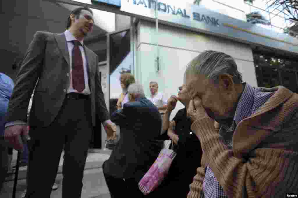 A bank manager explains the situation to pensioners waiting outside a branch of the National Bank of Greece hoping to get their pensions, in Thessaloniki, Greece, June 29, 2015.
