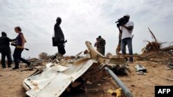 Journalists look at debris at the crash site of the Air Algerie Flight AH 5017 in Mali's Gossi region, west of Gao, July 26, 2014. 