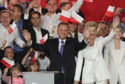 안제이 두다 폴란드 대통령이 지난 12일 치러진 폴란드 대선 결선 투표에서 유리한 출구 조사 결과가 나오자 부인, 딸과 함께 연단에 서서 지지자들을 향해 손을 흔들고 있다.