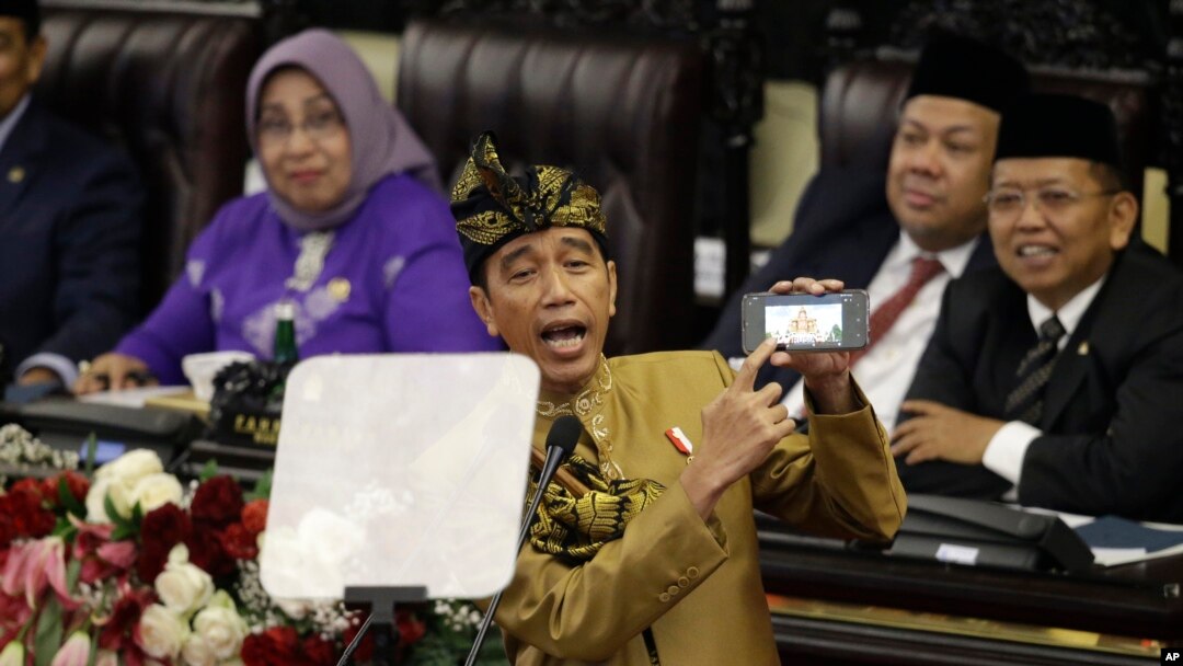 Presiden Joko Widodo, yang mengenakan busana tradisional Nusa Tenggara Barat, menunjukkan layar ponselnya saat menyampaikan pidato pada Sidang Tahunan dalam peringatan ulang tahun ke-74 Republik Indonesia.(Foto: AP)