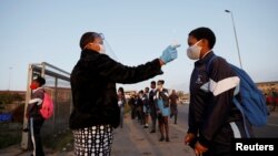 Prise de température avant l'ouverture d'une école dans le canton de Langa au Cap, en Afrique du Sud, le 8 juin 2020.
