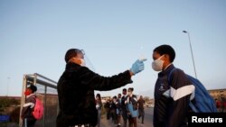 FILE - A student is screened as schools begin to reopen after the coronavirus disease lockdown in Langa township in Cape Town, South Africa, June 8, 2020.