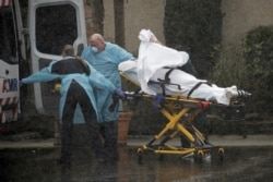 Medics transport a patient through heavy rain into an ambulance at Life Care Center of Kirkland, the long-term care facility linked to several confirmed coronavirus cases in the state, in Kirkland, Washington, March 7, 2020.