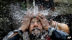 A Pakistani man cools himself off under a water supply to beat the heat during the holy fasting month of Ramadan, in Islamabad, Pakistan, June 7, 2016. 