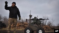 In this photo provided by Ukraine's 65th Mechanized Brigade press service, a serviceman explains how to operate a Gnom 2 ground drone in Zaporizhzhia region, Ukraine, on Nov. 29, 2024.