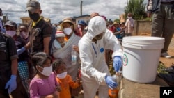 FILE - In this photo taken April 24, 2020, residents are given bottles of a herbal mixture said to prevent and cure COVID-19 in Antananarivo, Madagascar. 