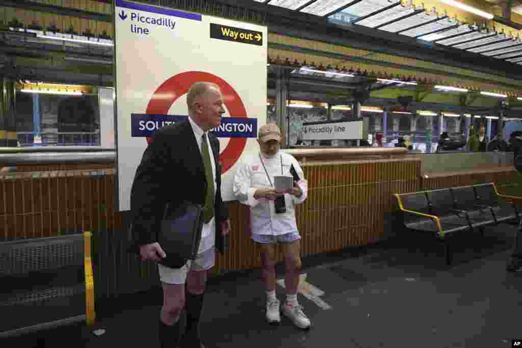 Two men wait for a tube at South Kensington station as they take part in the annual event &quot;No Trousers Tube Ride&quot; in London.