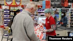 A cashier works behind a protective plexiglass shield at a supermarket in Sydney, Australia, Oct. 27, 2020.