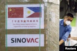 FILE - A worker unloads a box of Sinovac Biotech's CoronaVac vaccines from a Chinese military aircraft at Villamor Air Base in Pasay, Metro Manila, Philippines, Feb. 28, 2021.