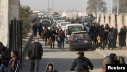 Displaced people who fled the Aleppo countryside walk past cars in Tabqa, Syria, Dec. 4, 2024.