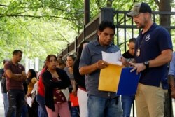 FILE - An Immigration and Customs Enforcement official gives direction to a person outside the building that houses ICE and the Atlanta Immigration Court, June 12, 2019.