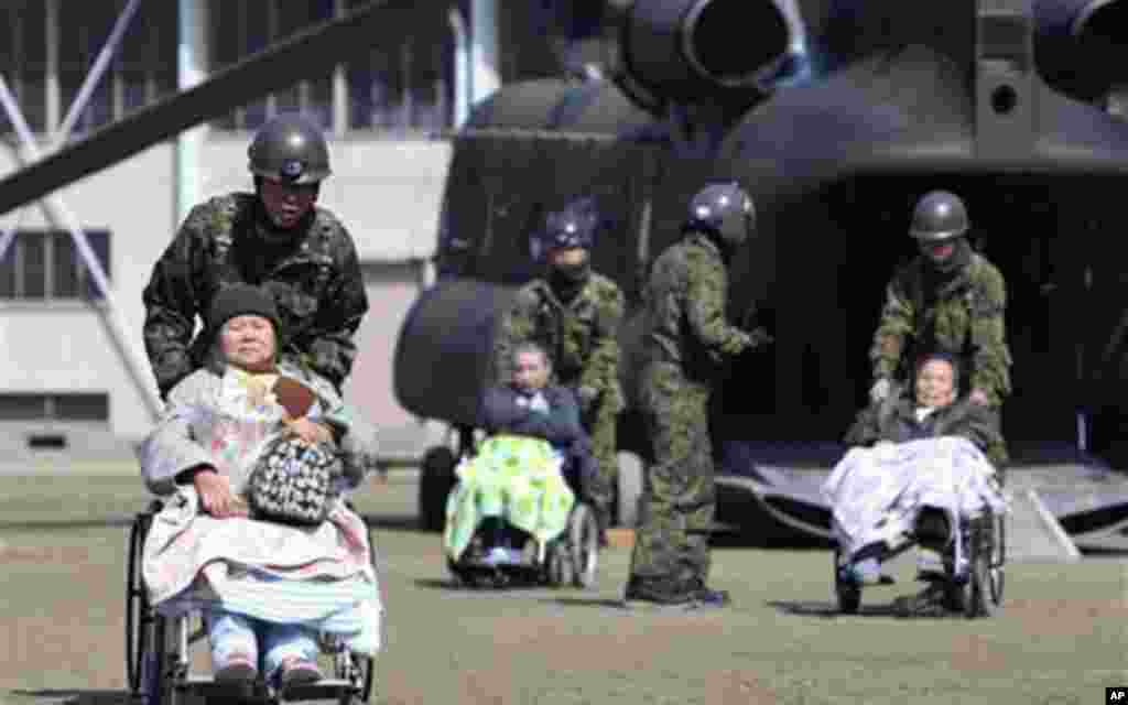 Futaba Kosei Hospital patients are assisted by Japan Self Defense Force personnel as they disembark from a helicopter in the compound of Fukushima Gender Equality Centre in Nihonmatsu, Fukushima Prefecture, northeastern Japan, March 13, 2011 – (AP)