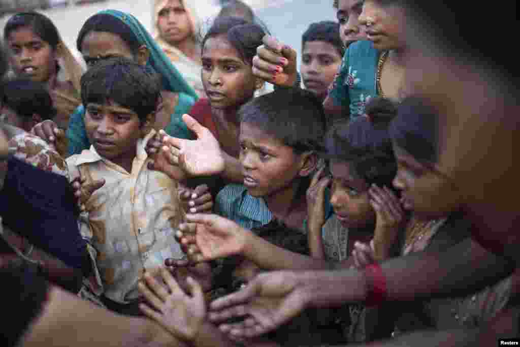 Anak-anak yang terlantar akibat meluapnya sungai Yamuna menunggu pembagian makanan gratis yang didistribusikan oleh relawan di luar tenda-tenda darurat di sebuah kamp di New Delhi, India.