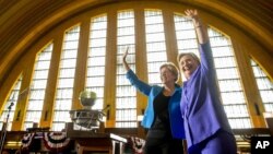 Democratic presidential candidate Hillary Clinton, accompanied by Sen. Elizabeth Warren, D-Mass., left, waves after speaking at the Cincinnati Museum Center at Union Terminal in Cincinnati, June 27, 2016.