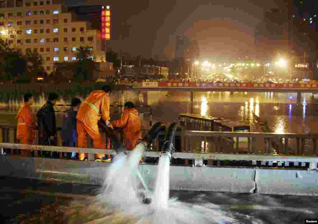Workers pump flood water near a stranded bus in Beijing, China, July 21, 2012.