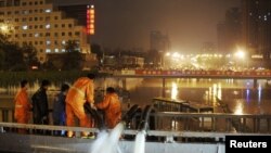 工作人员用水泵为北京街道排水，附近是一辆因大水被遗弃街头的巴士(7月21日)