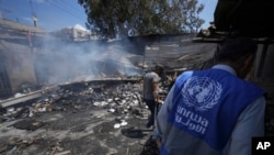 ARCHIVO. - Los palestinos observan la destrucción después de un ataque israelí contra una escuela dirigida por la UNRWA, la agencia de las Naciones Unidas que ayuda a los refugiados palestinos, en Nuseirat, Franja de Gaza, 14 de mayo de 2024. AP