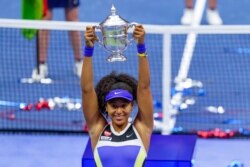 Naomi Osaka, of Japan, holds up the championship trophy after defeating Victoria Azarenka, of Belarus, in the women's singles final of the U.S. Open tennis championships, Sept. 12, 2020, in New York.