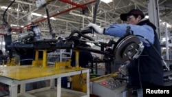 An employee works on an assembly line producing electronic cars at a factory of Beijing Electric Vehicle, funded by BAIC Group, in Beijing, China, Jan. 18, 2016. 