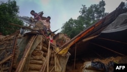 Rohingya refugees work Ju.y 27, 2021, amid the debris of a house in Balukhali camp that got damaged after monsoon rains triggered landslides and flash floods in Bangladesh.