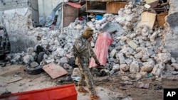 FILE - A soldier walks past wreckage in the aftermath of an attack on the Afrik Hotel in Mogadishu, Somalia, on Feb. 1, 2021. At least five people died in the attack by al-Shabab militants.