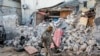 FILE - A soldier walks past wreckage after an attack on the Afrik hotel in Mogadishu, Somalia, Feb. 1, 2021. Though security forces eventually ended the attack, Somalia's government warned on Saturday that anyone who pays extortion money to al-Shabab would face legal action.