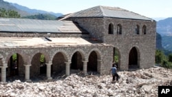 FILE - Workers build a guest house in the village of Nivica, southern Albania, July 18, 2017.