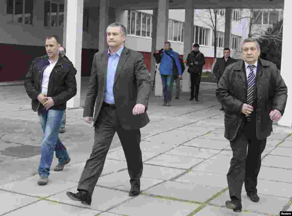 O primeiro-ministro crimeio Sergei Aksyonov (ao centro) sai depois de votar para o Referendo numa mesa de voto em Simferopol, Crimeia, Ucrânia, Março 16, 2014. 