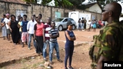 Un militaire assure la sécurité près des électeurs en fils lors du deuxième tour de la présidentielle à Freetown, Sierra Leone, 31 mars 2018.