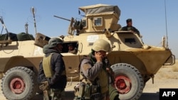 Afghan security forces stand near an armored vehicle during fighting between Afghan security forces and Taliban fighters in the Busharan area on the outskirts of Lashkar Gah, the capital of Helmand province, May 5, 2021. 