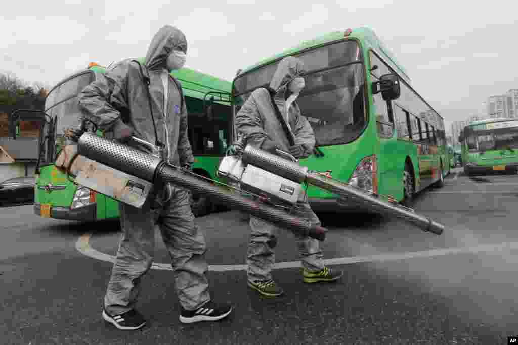 Workers wearing protective suits spray disinfectant as a precaution against the coronavirus, at a bus garage in Seoul, South Korea.