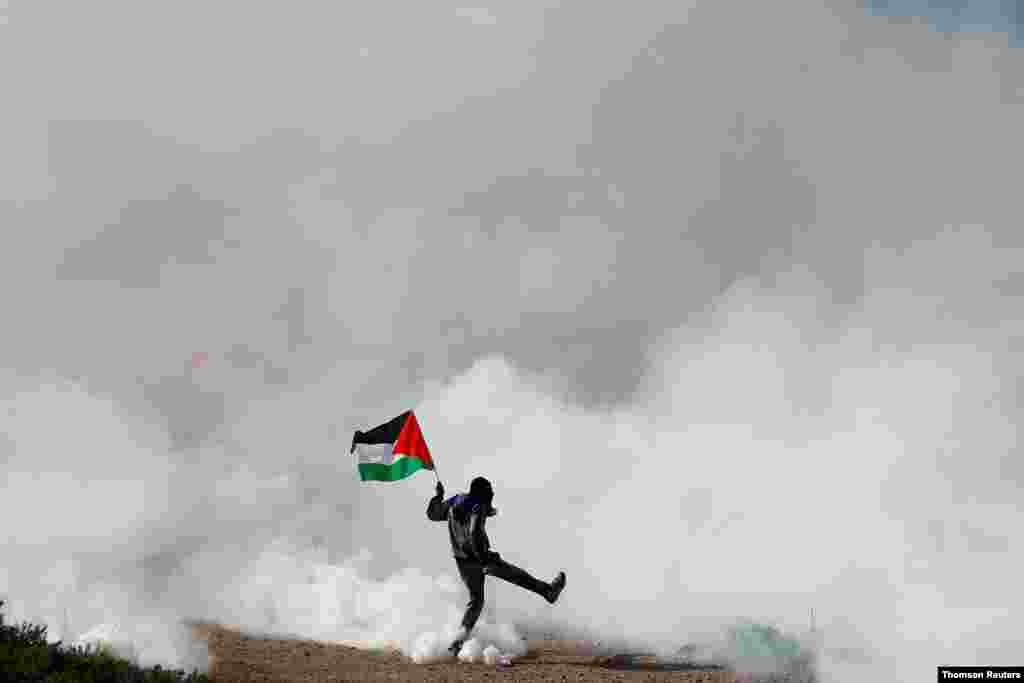 요르단강 서안지구의 유대인 정착을 반대하는 팔레스타인 시위 참가자가 이스라엘군이 쏜 최류탄 연기를 피하고 있다. 