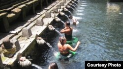 Turis asing mandi-mandi di air mancur Tirta Empul di Bali. 