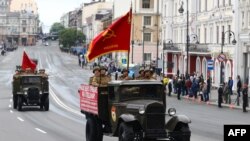 Participants wearing historical uniforms ride in the back of a WWII-era truck during a military parade, which marks the 75th anniversary of the Soviet victory over Nazi Germany in World War Two, in the far eastern city of Vladivostok on June 24, 2020.
