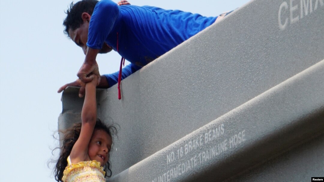 Un hombre ayuda a una niña a subirse a un vagón mientras se unen a otros migrantes centroamericanos (no fotografiados) en el tren de carga conocido como "La Bestia" durante su viaje hacia Estados Unidos, en Ixtepec, México.