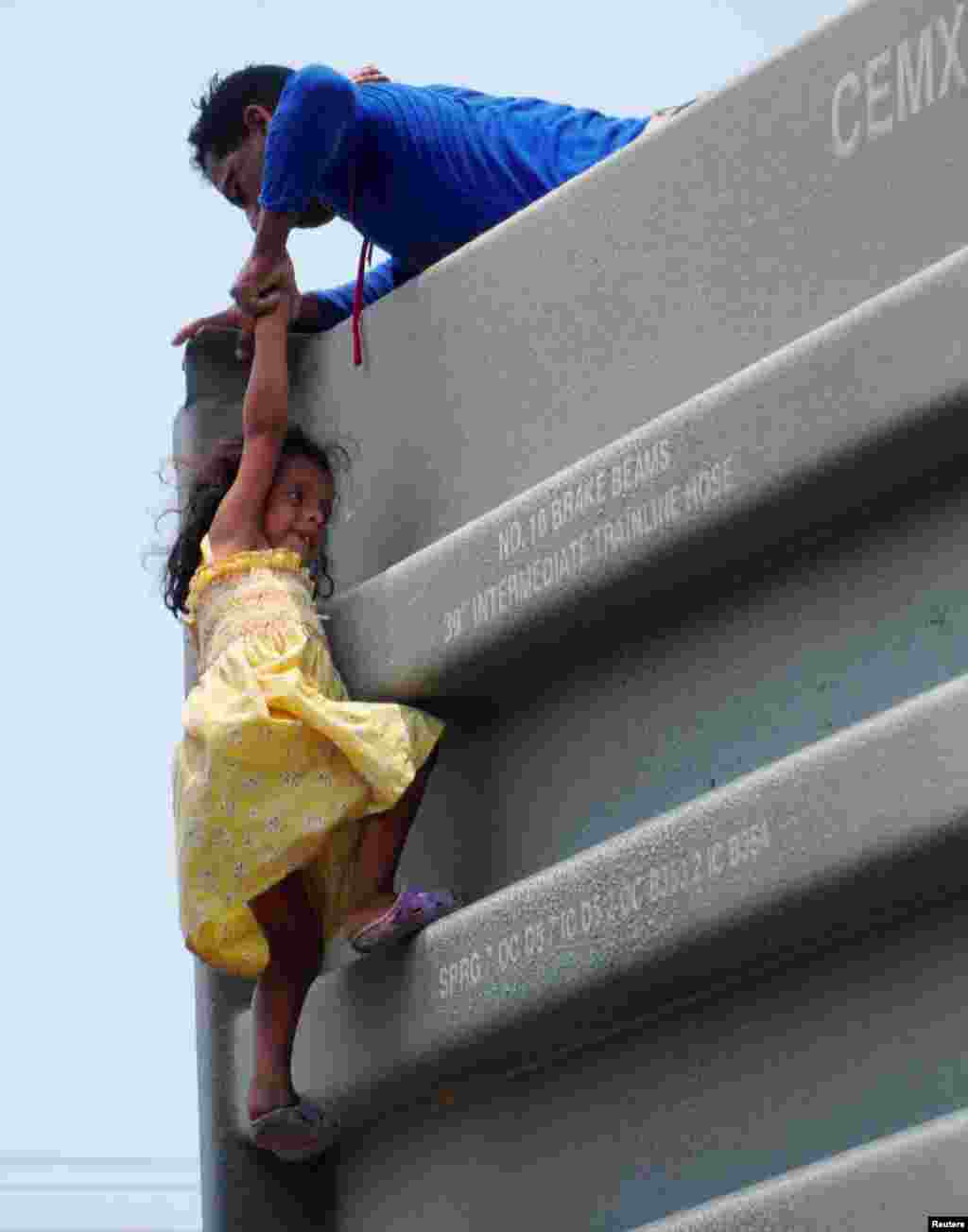 A man helps a girl to climb onto a boxcar as they join other Central American migrants (not pictured) in the freight train known as &quot;The Beast&quot; in Ixtepec, Mexico, during their journey toward the United States, April 30, 2019.