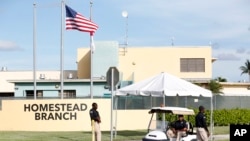 Security guards stand outside a former Job Corps site that now houses child immigrants, June 18, 2018, in Homestead, Fla. It is not known if the children crossed the border as unaccompanied minors or were separated from family members.