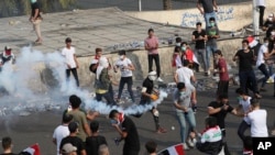 Para pemrotes anti-pemerintah melemparkan gas air mata yang ditembakkan oleh polisi di Baghdad, Irak, 28 Oktober 2019.