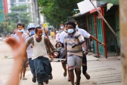 Un hombre que fue herido en las manifestaciones contra el gobierno de Yangón, Myanmar, hace el saludo de los tres dedos mientras lo saca de la zona de impacto de los enfrentamientos el 15 de marzo de 2021.