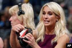 In this Nov. 9, 2018, file photo, Sarah Kustok, television sports reporter for the Brooklyn Nets, prepares for the team's NBA basketball game against the Denver Nuggets in Denver.