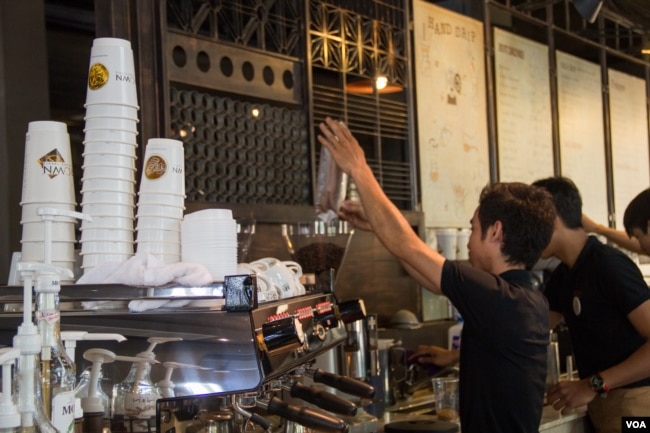 This coffee shop employee is pouring coffee beans into a coffee bean grinder, 2015. (Nov Povleakhena/VOA Khmer)