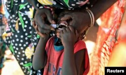 FILE - A displaced South Sudanese child receives an oral cholera vaccine in a camp for internally displaced people in the United Nations Mission in South Sudan compound in Tomping, Juba, in February 2014.